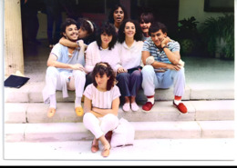 La fotografía captura a un grupo de amigos jóvenes, sentados en una escalera de piedra, posiblemente en el edificio de dirección de La Laboral, mostrando una atmósfera relajada y amistosa propia de los años 80.